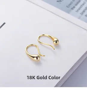 Detail of 18K gold teardrop earrings with polished finish and elegant curved hooks