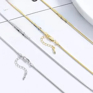 Close-up of minimalist silver and gold snake chains with lobster clasp and extender