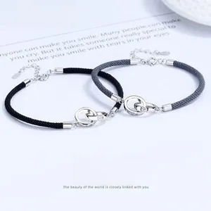 Detail of Mobius interlocking silver rings on black and grey woven couple bracelets