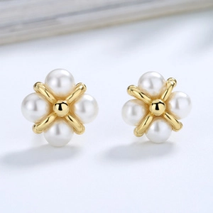 Macro view of S925 silver pearl stud earrings featuring a golden cross flower design