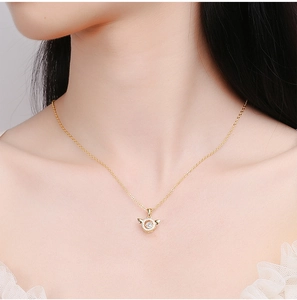 Détail du collier ailes d'ange doré avec un cœur dansant en zircone sur modèle