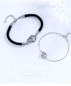 Close-up of interlocking S925 silver rings with Keep Me In Your Heart engraving on woven rope