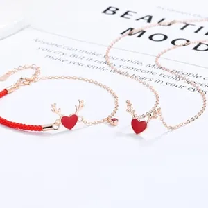 Detail of a 925 silver red enamel heart necklace with golden antlers and red cord bracelet