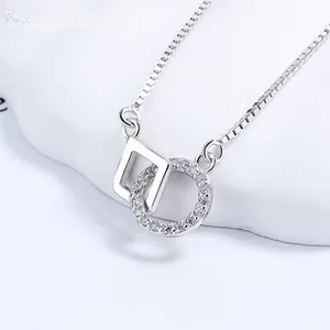 Detailed macro of silver interlocking square and zircon round pendant on box chain