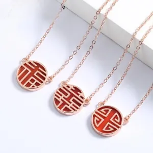 Macro shot of rose gold necklaces featuring Chinese characters and red agate details