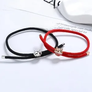 Detail of red and black woven couple bracelets with silver cat-shaped koi charms