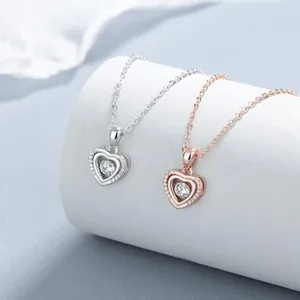 Detail of silver and rose gold heart pendants with floating center stones and tiny diamonds
