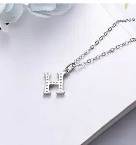 Macro detail of silver S925 H-letter pendant with crystal pavé and mirror polished finish