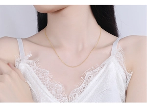 Detailed view of an adjustable gold s925 silver ball chain necklace on a female model