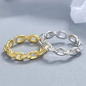 Macro view of adjustable chain link rings in gold and silver finishes on a grey background