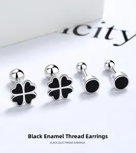 Detail of S925 silver black clover and round screw back stud earrings set on paper