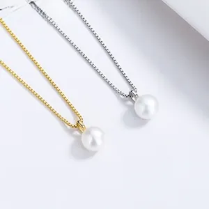 Détail de pendentifs en perles argent et or avec chaînes élégantes sur fond blanc épuré