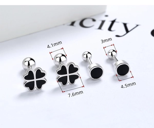 Macro detail of silver stud earrings with black enamel clover and round designs