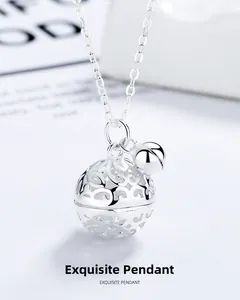 Detailed macro view of S925 sterling silver hollow bell pendant on a delicate cross chain