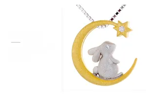 Macro view of matte silver bunny and gold moon pendant with white crystals