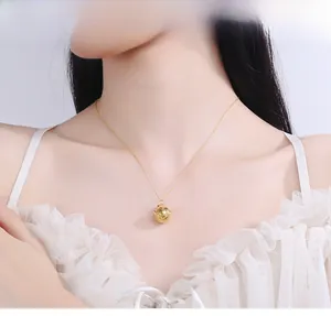 Detail view of the elegant hollow golden bell pendant on a delicate chain worn by a model