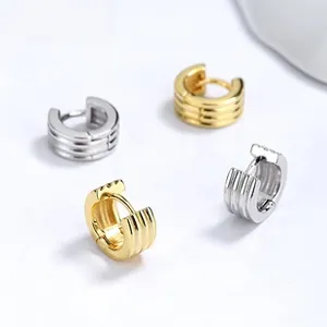 Detailed view of silver and gold octagonal earrings with textured parallel grooved design