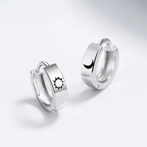 Macro detail of 925 sterling silver hoop earrings with sun and moon laser engravings