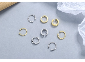 Close-up of assorted silver and gold ear cuffs with twisted and smooth textures