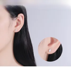 Close-up of a minimalist S925 silver earring with a rectangular zircon on an ear model