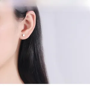 Gros plan de boucles d'oreilles minimalistes en argent portées sur le lobe d'un mannequin