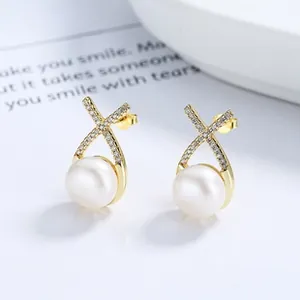 Vista macro di orecchini in argento 925 con perle e design a croce con zirconi