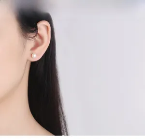 Primo piano di un orecchino a bottone con perla bianca su modella per un look elegante