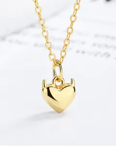 Detalle macro de un collar con colgante de corazón de diablo dorado y acabado espejo pulido