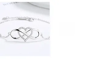 Macro detail of silver infinity heart bracelet with cubic zirconia and dainty O-chain