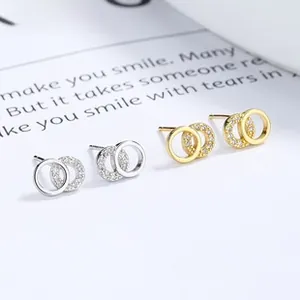Close-up of dual interlocking rings earrings in gold and silver with cubic zirconia