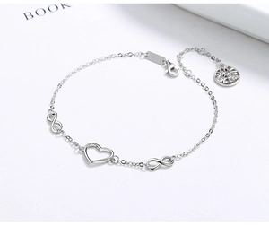 Detailed view of silver infinity and heart bracelet with tree of life pendant