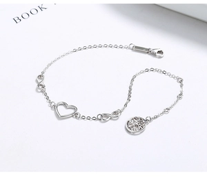 Macro shot of 925 silver bracelet featuring hollow heart, infinity and tree of life charms