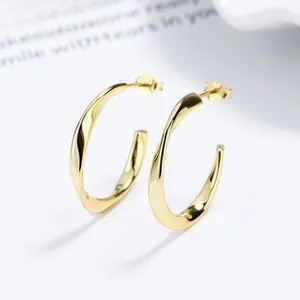 Close-up of polished gold twisted hoop earrings with a mirror-like high quality finish