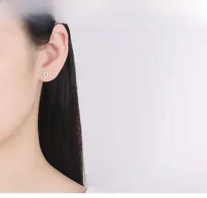Close-up of geometric S925 silver stud earrings with pavé zircons on a model's ear