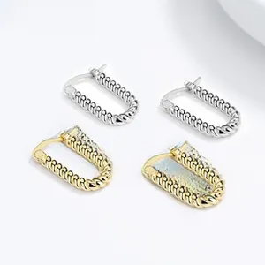 Vue détaillée des boucles d'oreilles torsadées en U, finitions or 18k et argent poli