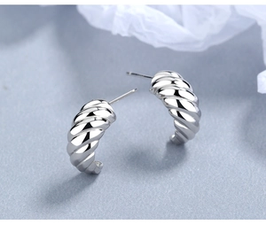 Macro shot of silver croissant-style C-shaped hoop earrings with twisted metallic texture