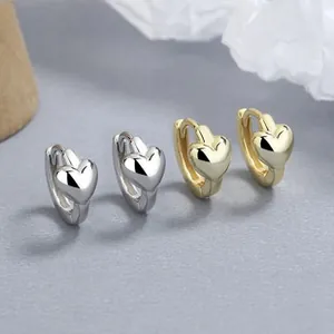 Detailed view of polished heart-shaped silver and gold hoop earrings on art paper
