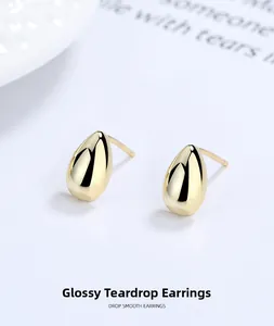Macro shot of minimalist gold-plated teardrop stud earrings with polished mirror finish