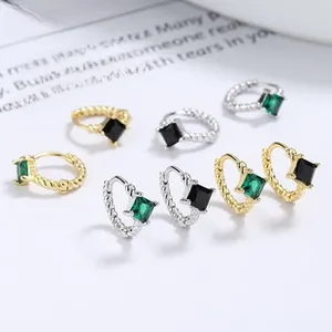 Detail of twisted 925 silver hoop earrings with square emerald and black gemstones
