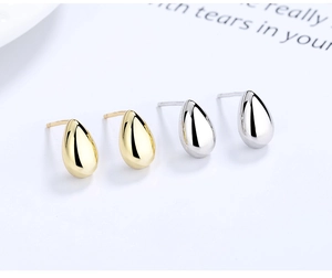 Macro shot of polished gold and silver water drop earrings in minimalist style