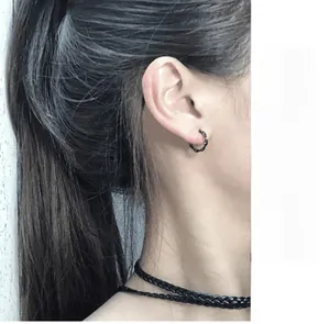 Close-up of minimalist black Mobius twisted hoop earrings on model for a trendy chic style