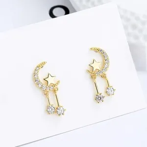 Detailed view of gold star and moon drop earrings with sparkling white cubic zirconia