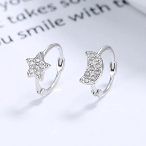Macro shot of 925 sterling silver hoop earrings with zircon pavé moon and star charms