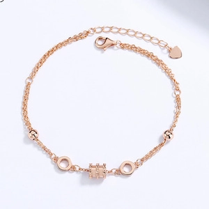 Detail of rose gold double-layer chain with beads and textured cylinder charm