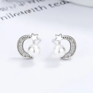 Macro view of 925 silver crescent moon and star earrings with round white pearl