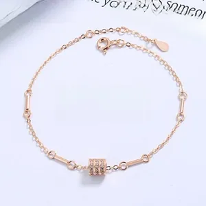 Macro shot of rose gold cylinder charm bracelet with sparkling zircons on blue background