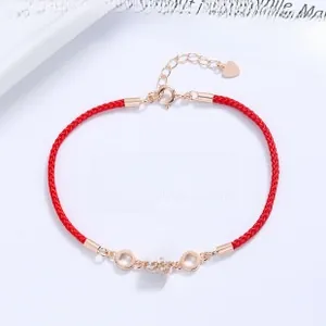 Close-up of rose gold waist cylinder pendant on red braided rope bracelet with zircon