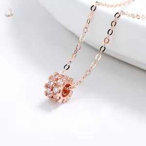 Close-up of rose gold cylindrical pendant with micro-set zircons on a delicate chain