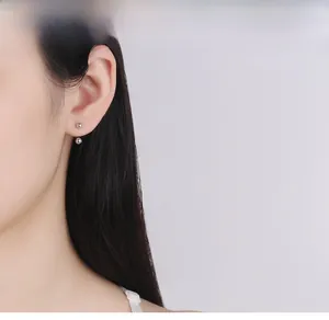 Detailed view of silver S925 U-shaped screw back ball earrings on model's ear