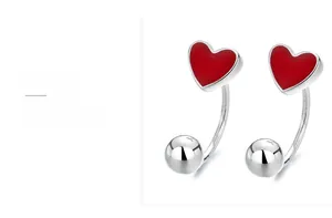 Macro shot of 925 sterling silver heart earrings with red enamel and silver beads